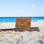 Save the Planet sign on a sunny beach, promoting eco-friendly tourism practices